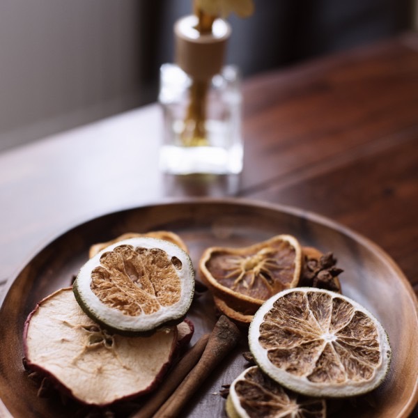 Holzteller mit getrockneten Limetten, Apfel und Zimt für Aroma-Behandlungen