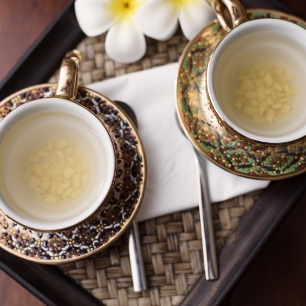 Zwei vergoldete Tassen Thai-Tee mit Plumeria-Blüte