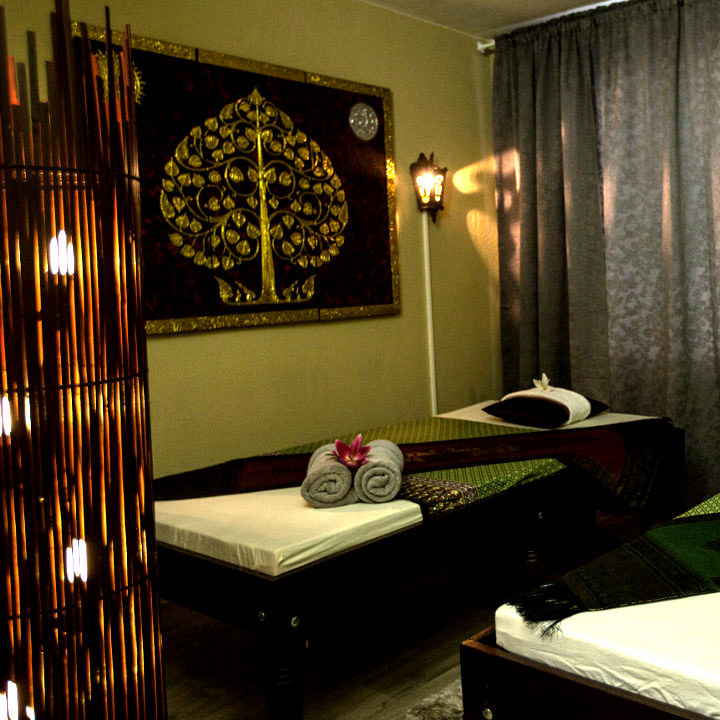 Behandlungsraum mit Bodhi-Baum-Bild und Massageliege
