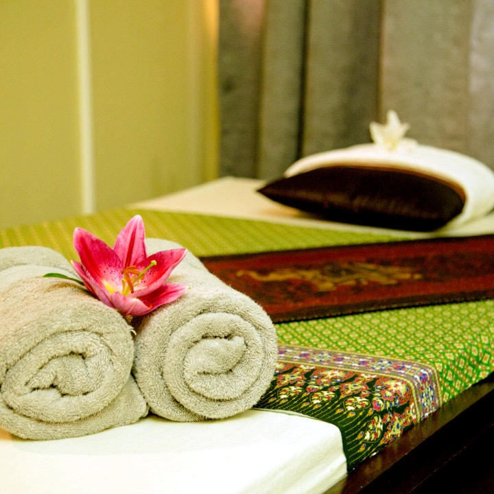 Gerollte Tücher mit pinker Lilie auf einer Thai-Matte